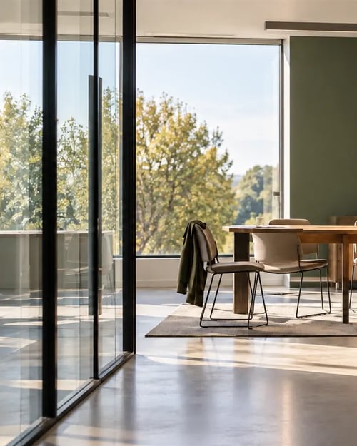 Sunlit meeting space with floor-to-ceiling windows overlooking trees.